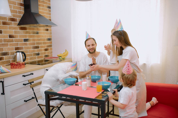 přátelská veselá rodina sedět slaví narozeniny doma se psem - Fotografie, Obrázek