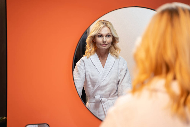ernsthafte kaukasische Frau steht vor dem Spiegel - Foto, Bild