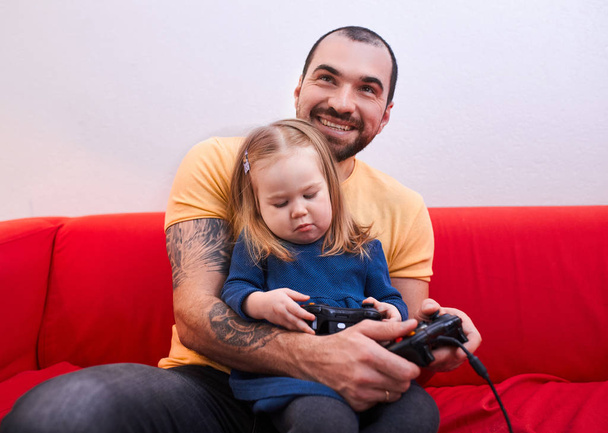 cheerful father and daughter sit playing video game - Fotó, kép