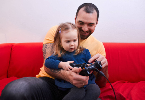 joyful parent father and sweet cute girl play video game - Foto, afbeelding