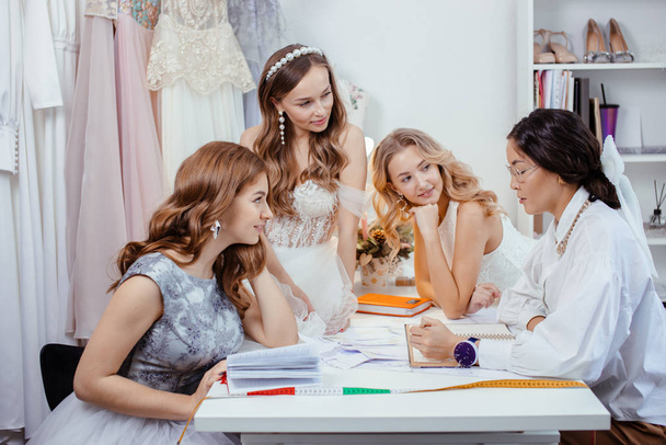 good-looking designer tailor of wedding dresses and young women - Foto, immagini