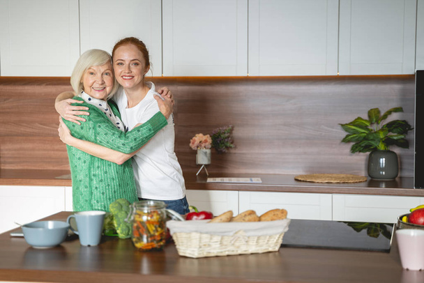 Cheerful mature woman embracing her young volunteer - Photo, Image