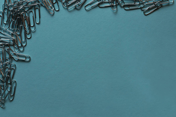 metallic paper clips lying on a blue paper - Фото, изображение