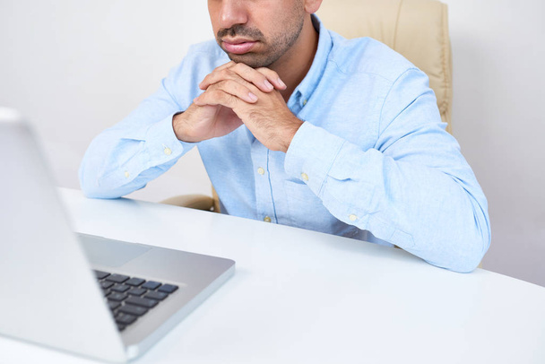 Müder Geschäftsmann sitzt am Schreibtisch und liest langweilige E-Mails von Kunden oder Geschäftspartnern - Foto, Bild