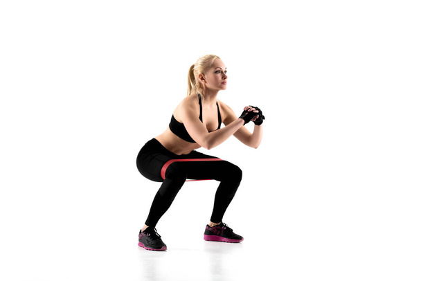 La ragazza esegue squat con un espansore durante l'allenamento
. - Foto, immagini