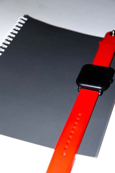 Gray notebook for writing on black background. Ballpoint pen. Smart watch with a red strap. Flat Lai, copies of the paste. View from different sides. Smartphone. Businessmen set kit white background. - Foto, Imagen