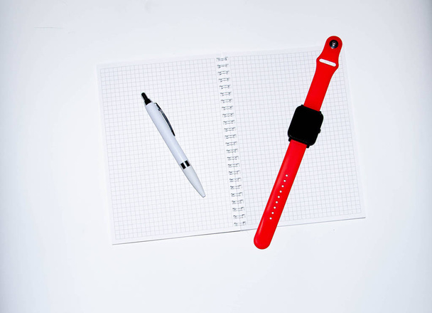 黒の背景に書くための灰色のノート。ボールペン。赤いストラップとスマートウォッチ。フラットライ、ペーストのコピーします。異なる側面からの眺め。スマートフォン。ビジネスマンセットキット白の背景. - 写真・画像