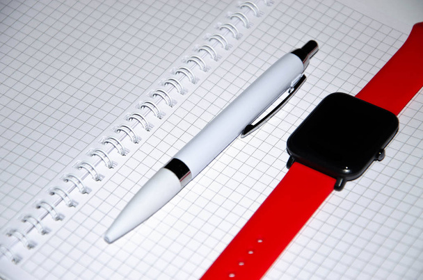 Gray notebook for writing on black background. Ballpoint pen. Smart watch with a red strap. Flat Lai, copies of the paste. View from different sides. Smartphone. Businessmen set kit white background. - Photo, Image
