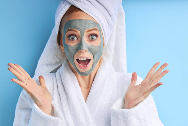 Surprised woman in bathrobe and towel use cosmetic mask - Foto, Imagen