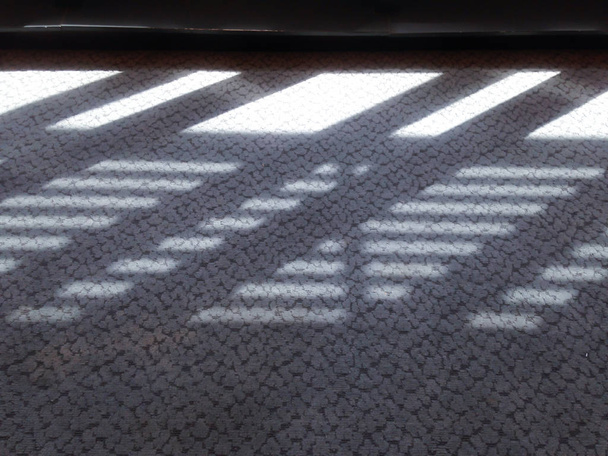 Βιομηχανικός σχεδιασμός παράθυρο φως του ήλιου παράλληλες γραμμές σκιές. Φως και σκιά από το παράθυρο αντανακλάται στο χαλί. Θέση για το κείμενο σας. - Φωτογραφία, εικόνα