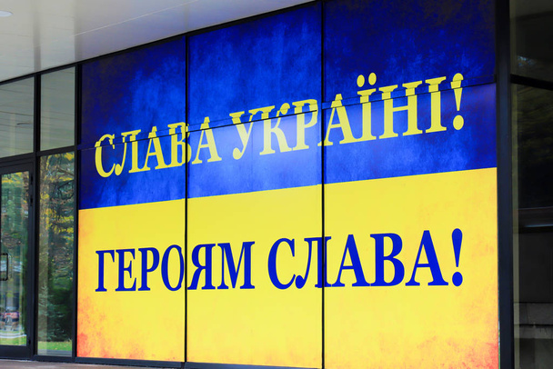 Bandeira azul amarelo nas cores da bandeira ucraniana com o slogan em ucraniano - Glória à Ucrânia! Glória aos heróis! sobre a construção da administração estatal de Dnepropetrovsk. Cidade de Dnipro
 - Foto, Imagem