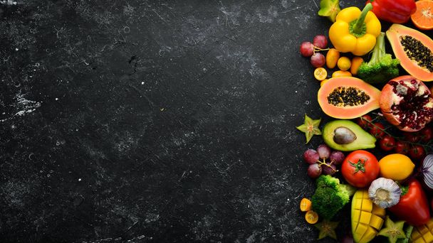 Vegetables and fruits, healthy food. Fruits and vegetables on black stone background. Tropical fruits. Top view. Free space for your text. - Photo, image