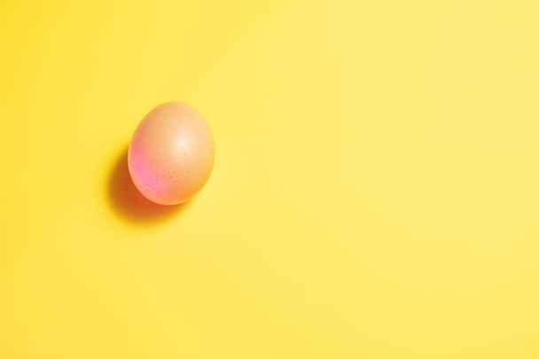 Свежее пасхальное яйцо на жёлтом фоне. Счастливая Пасха
 - Фото, изображение