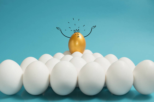 Recrutement d'entreprises, gestion des talents. Un œuf doré avec couronne en haut du groupe des œufs blancs sur fond bleu
.  - Photo, image