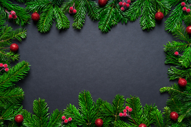 Weihnachtsrahmen mit Tannenzweig und Christbaumkugeln auf schwarzem Hintergrund - Foto, Bild