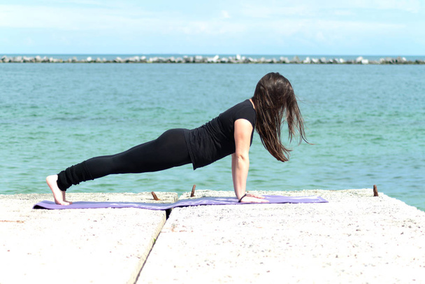 menina esportiva fazendo ioga, estendendo-se em direção ao mar. Asana. estilo de vida saudável. treinador de fitness. bela mulher no litoral
 - Foto, Imagem