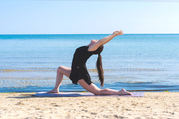 Sportliches Mädchen beim Yoga, das sich in Richtung Meer streckt. Asana. Gesunder Lebensstil. Fitness-Trainer. schöne Frau an der Küste. Tänzer - Foto, Bild