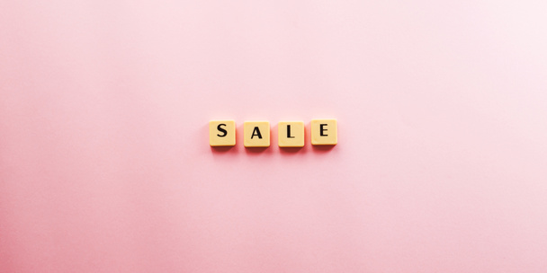 Sale word composed with plastic tiles on pink - Photo, image