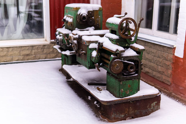 παροπλισμένος απαρχαιωμένος εξοπλισμός στέκεται στο χιόνι έξω - Φωτογραφία, εικόνα