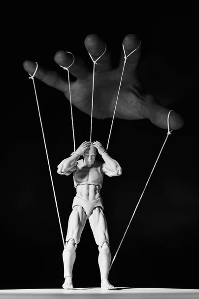 Concept of control. Marionette in human hand. Black and white image - Photo, Image