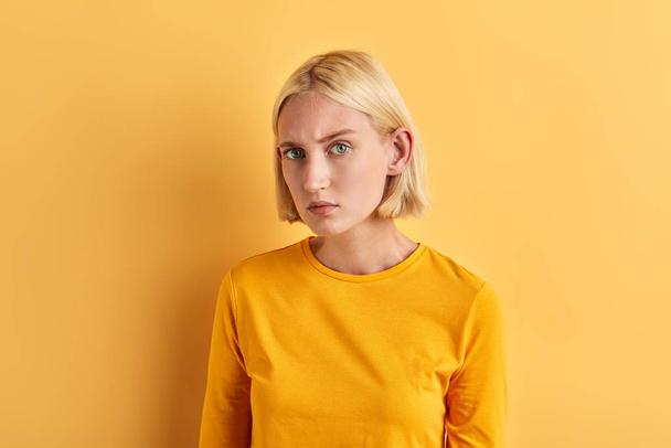serious skeptic woman in fashion yellow sweater posing to the camera - Fotoğraf, Görsel