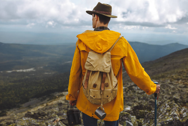 young man in yellow raincoat spending time in mountain - Photo, Image