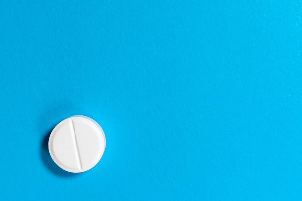 One white pill on a blue background. Copy space. Medicine, health. - Фото, изображение