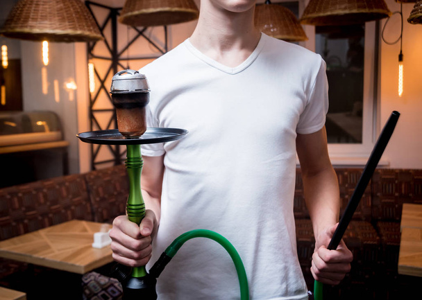 Cooking hookah in the bar. Young man with hookah in restaurant, hookah bar, smoking cafe. - Photo, image