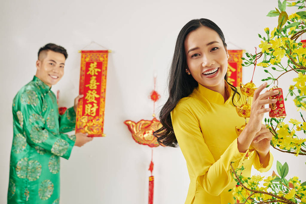 Hermoso feliz joven pareja decorando apartamento para la celebración del Año Nuevo Lunar
 - Foto, imagen