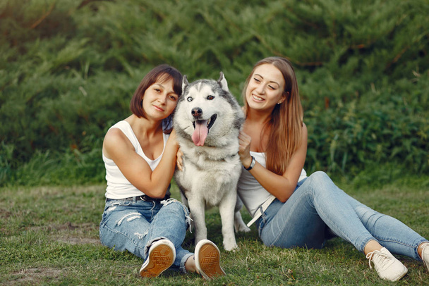 Dos chicas en un parque de primavera jugando con un lindo perro
 - Foto, Imagen
