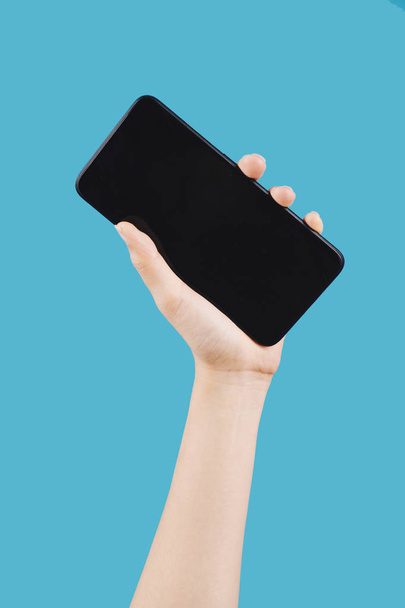 Frauenhand hält Großbildschirm-Smartphone vor blauem Hintergrund - Foto, Bild