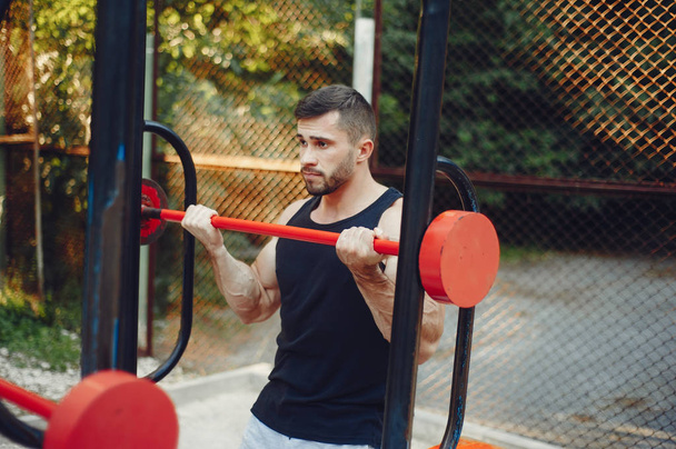 Handsome man training in a summer park - Foto, Bild