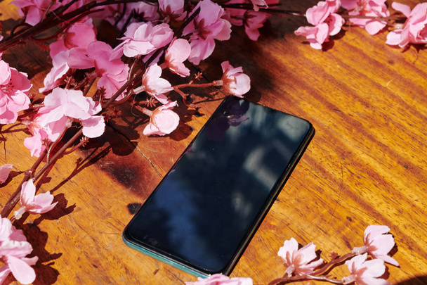 Smartphone con pantalla vacía en mesa de madera con ramas de melocotón en flor
 - Foto, Imagen