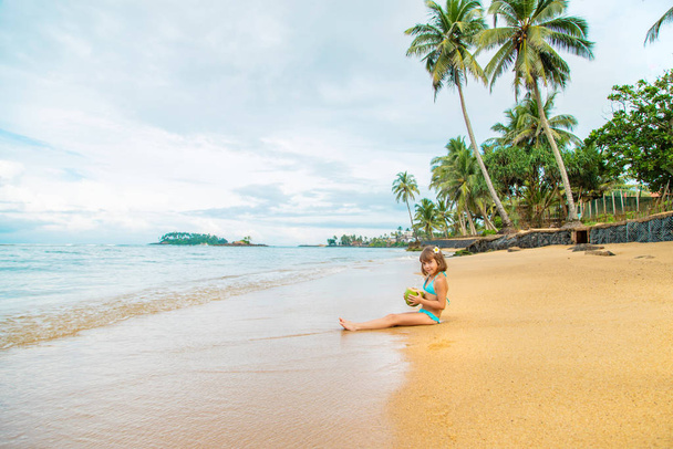 A child on the beach drinks coconut. Selective focus. - Zdjęcie, obraz