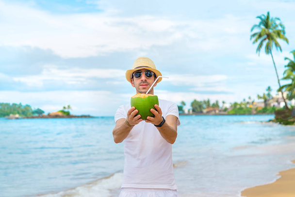 A man on the beach drinks coconut. Selective focus. - Fotó, kép