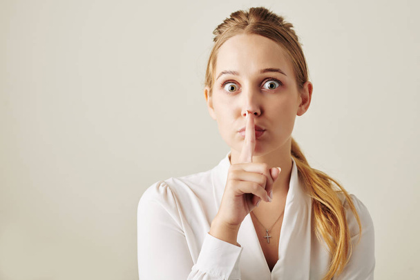 Young business lady making silence gesture and looking at camera - Foto, Imagen