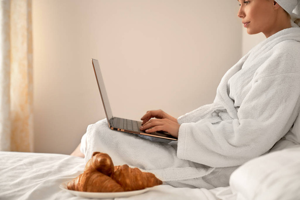 Woman in bathrobe typing on laptop. - Foto, Imagem