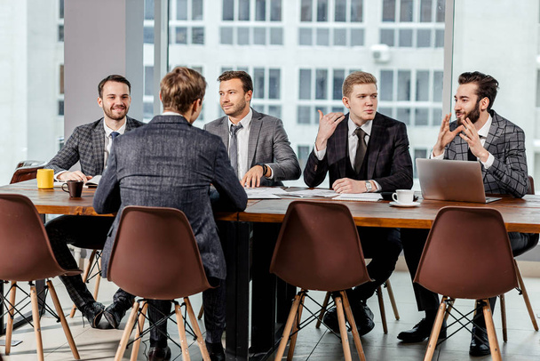 młodzi mężczyźni w garniturach zebrani na spotkaniu biznesowym - Zdjęcie, obraz