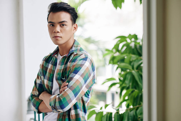 Portret przystojnego, pewnego siebie młodego Wietnamczyka w kratę, składanych ramionach i patrzącego w kamerę - Zdjęcie, obraz