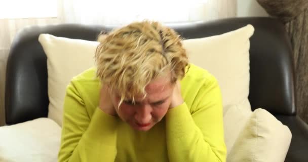 Mujer dolorosa sentada en un sofá en casa y masajeando su cuello y hombro - Metraje, vídeo