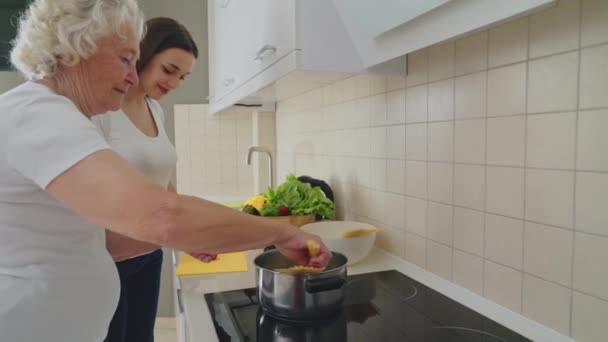 Smiling woman helping grandmother to cook. - Imágenes, Vídeo