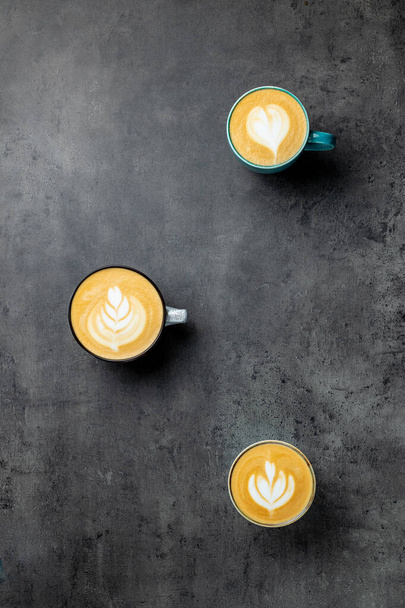 3 Tassen Kaffee auf grauem Hintergrund Draufsicht. Cappuccino Latte und flaches Weiß - Foto, Bild