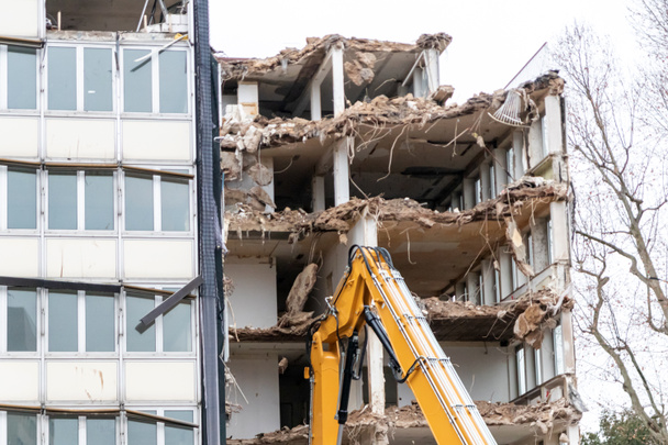 Demolition of a building at a construction yard in the city with heavy machinery like bulldozers and hydraulic excavator as construction equipment do rebuild urban architecture with broken industry - Photo, Image