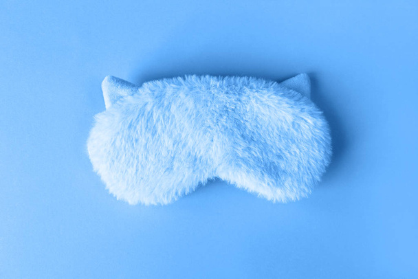Fluffy fur sleep mask with small ears on paper background. Top view, flatlay. Accessories for girls and young women in Classic Blue colour, close-up, top view. Color of the year 2020 concept - Foto, Bild