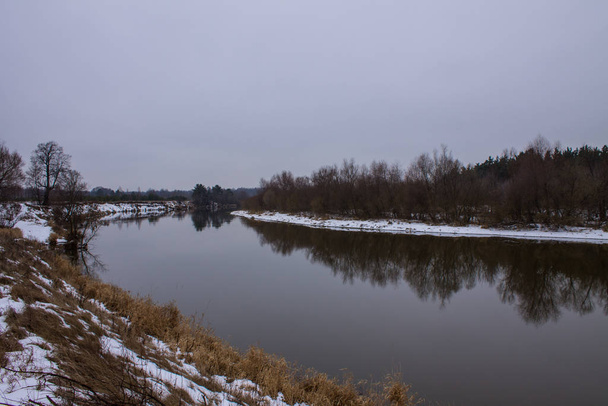 Winter landscape with river and reflections and snow on the Bank on a cloudy day - Foto, Imagem