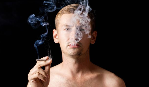 muotokuva mustalla taustalla, kaveri savuke kädessä polttaa
 - Valokuva, kuva