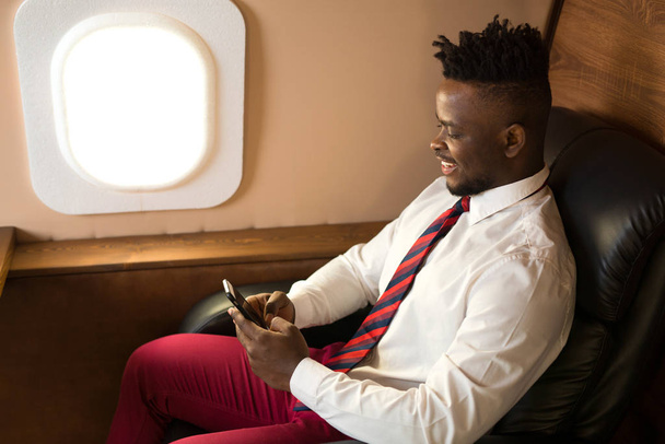 handsome african man in white shirt in airplane chair - Foto, imagen