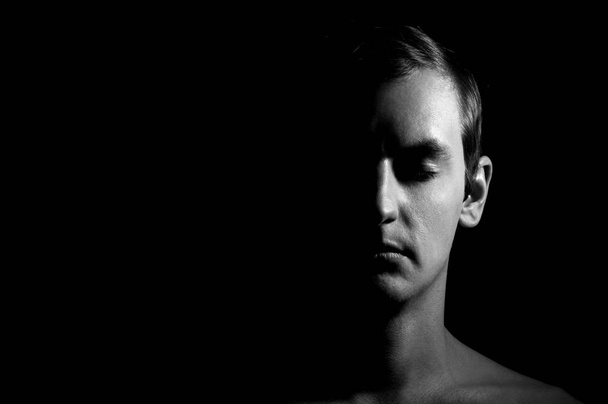 Dramatic portrait of a guy on a black background, black and white photography - Fotó, kép