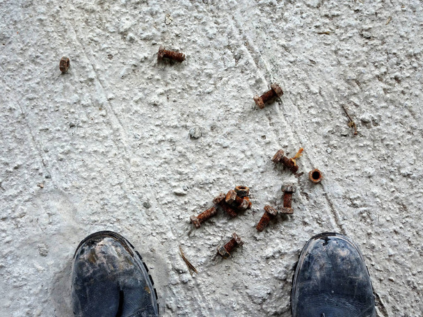 Ржавый болт и гайка на грязном бетонном полу
.  - Фото, изображение