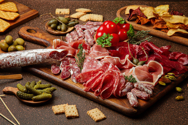 Appetizers table with differents antipasti, cheese, charcuterie, snacks and wine. Sausage, ham, tapas, olives, cheese and crackers for buffet party. - Photo, Image